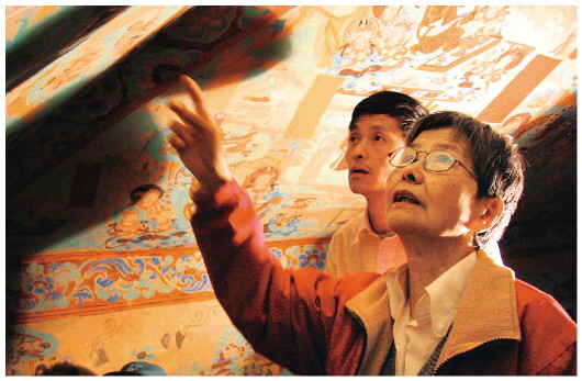 ▲樊锦诗（右一）在莫高窟第八十五窟壁画修复现场。（敦煌研究院供图）