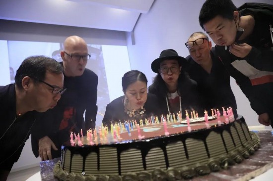北京，“人人都是艺术家——约瑟夫·博伊斯百年诞辰纪念活动”现场，众人切生日蛋糕为约瑟夫·博伊斯庆生。蛋糕上插了100根蜡烛